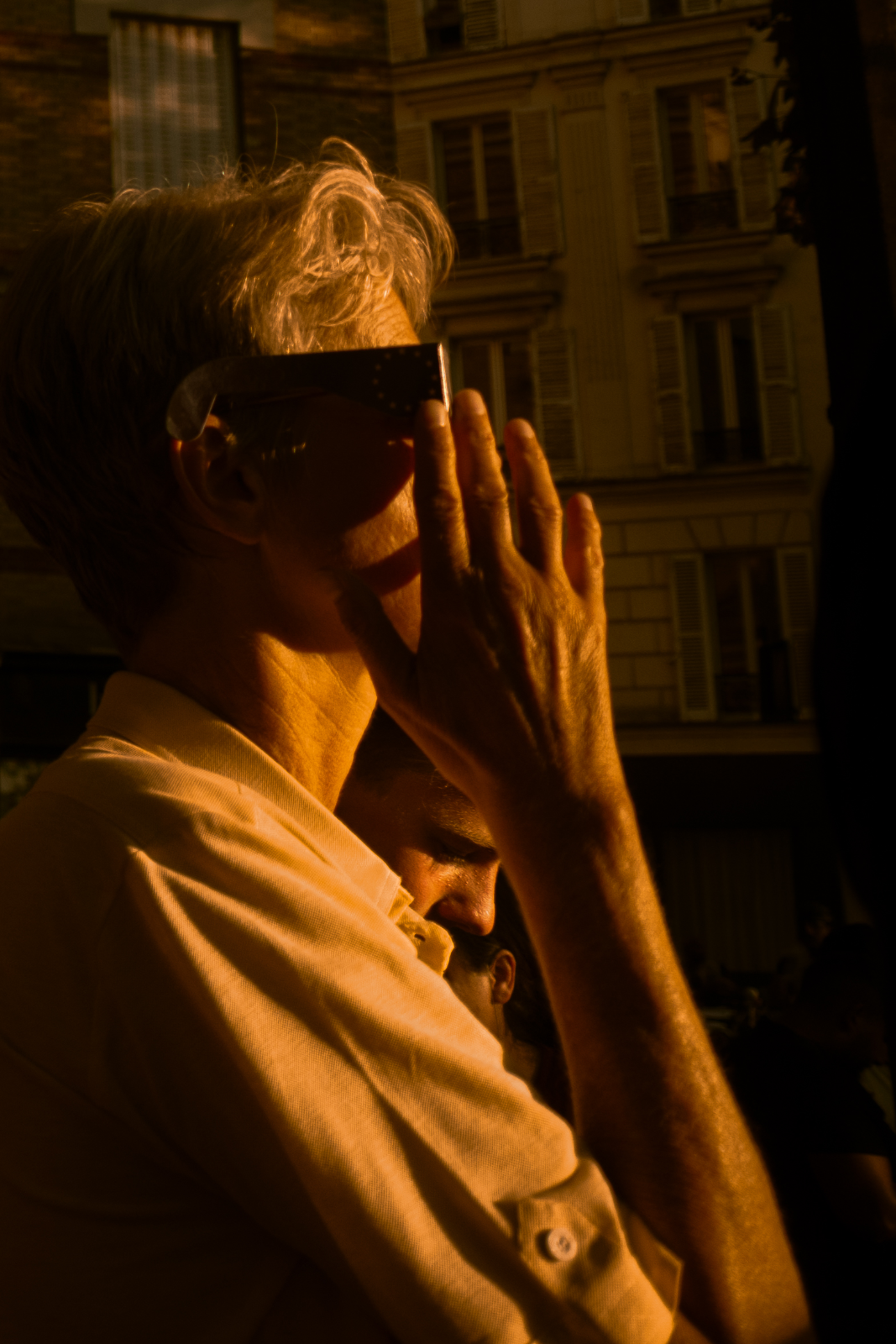 Homme aux cheveux blancs, main levée, lunettes d'éclipse